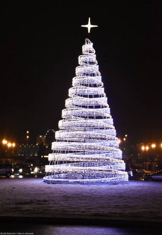 Rosnąca wysoko w niebo choinka bożonarodzeniowa ozdobiona mnóstwem błyszczących, śnieżnobiałych lampek. Na samym jej szczycie umieszczona jest olśniewająca, złota gwiazda. To imponująca, świąteczna dekoracja, która rozświetla i radosnym blaskiem wypełnia centrum miasta Białystok.