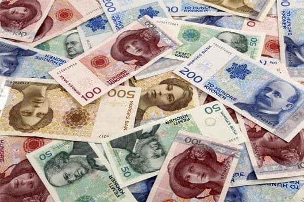 Zdjęcie przedstawia stos norweskich banknotów i monet ułożonych jedne na drugich. Widoczne są nominały w koronach norweskich. Fotografia nawiązuje do tematu zwrotu podatku z Norwegii i ma zachęcić odbiorców do skorzystania z usług firmy KDF-Podatki w celu odzyskania nadpłaconego podatku z tego kraju.